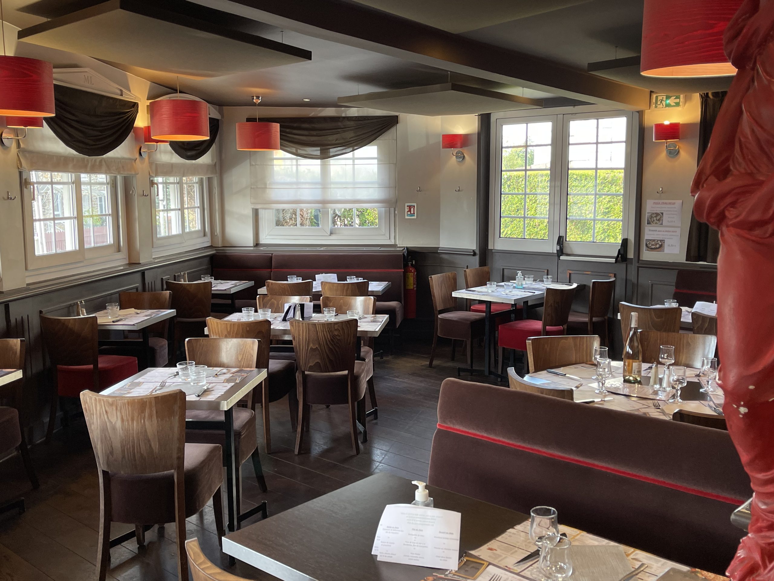 Intérieur traditionnel du restaurant Mona Lisa à Villiers-sur-Marne dans le Val-de-Marne (94) où l'on aperçoit des chaises en bois rustiques et des tables assorties. Les fauteuils de couleur marron ajoutent une touche de confort à l'atmosphère chaleureuse. Les murs blancs offrent une toile de fond épurée qui met en valeur l'authenticité et la simplicité élégante du lieu.